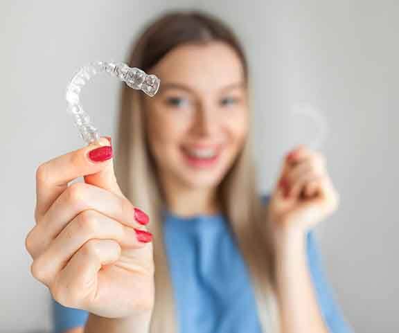 Young woman with red nails holding Invisalign trays